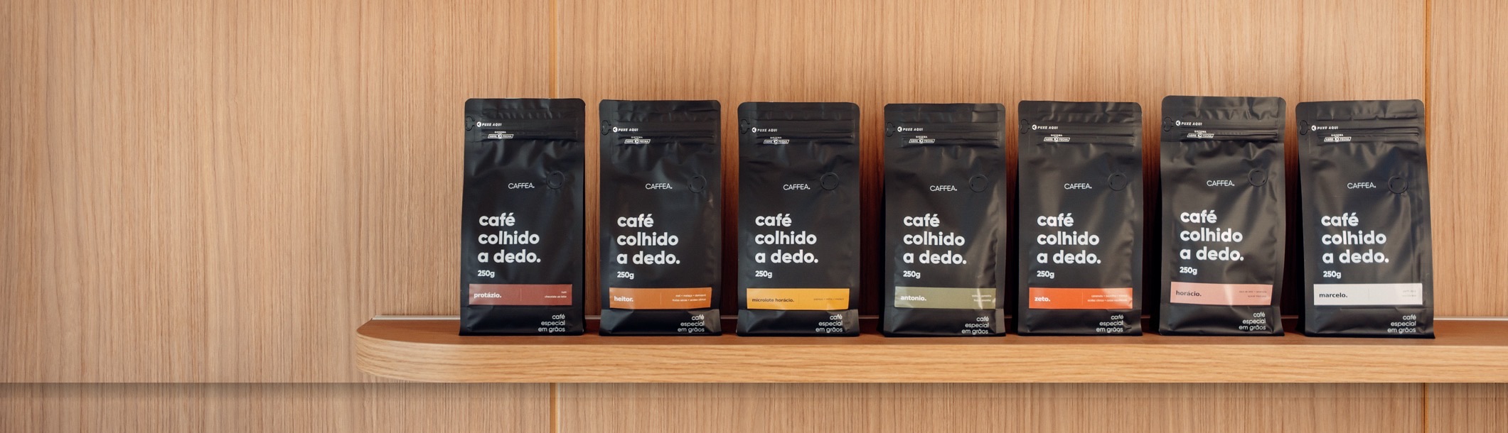 Os sete cafés CAFFEA lado a lado na prateleira de madeira